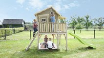 Domček cédrový na pilieroch Crooky 750 Exit Toys s verandou vodeodolnou strechou 2,28 m šmykľavkou a pieskoviskom sivo béžový